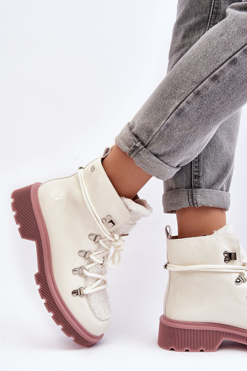 Casual winter boots with lace-up design on an individual wearing rolled-up jeans against white background.
