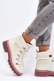 Casual winter boots with lace-up design on an individual wearing rolled-up jeans against white background.