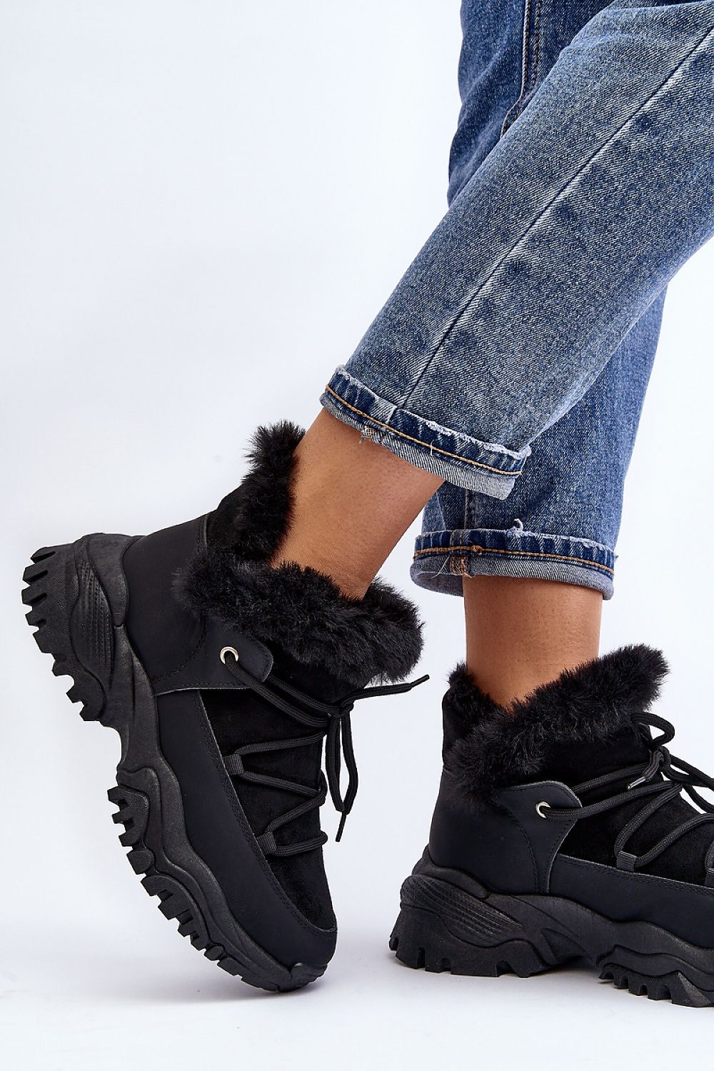 Velora faux fur-lined winter sneakers in black, trapper-style, eco leather, with lacing and platform heel, paired with denim jeans.