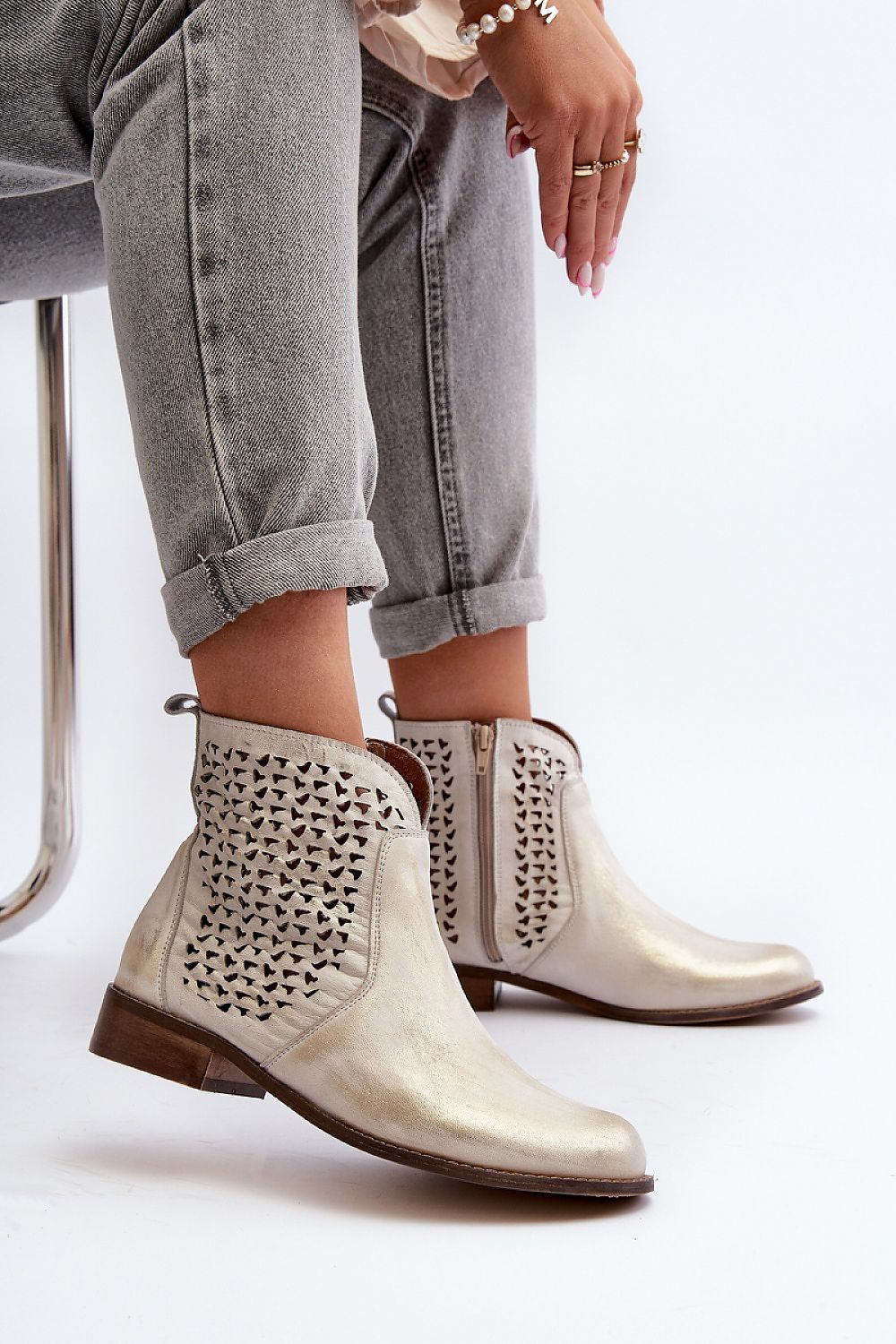 Velenna Openwork Leather Zip Boots with decorative cutouts, side zipper, and low heel, styled with cuffed jeans for casual chic look.
