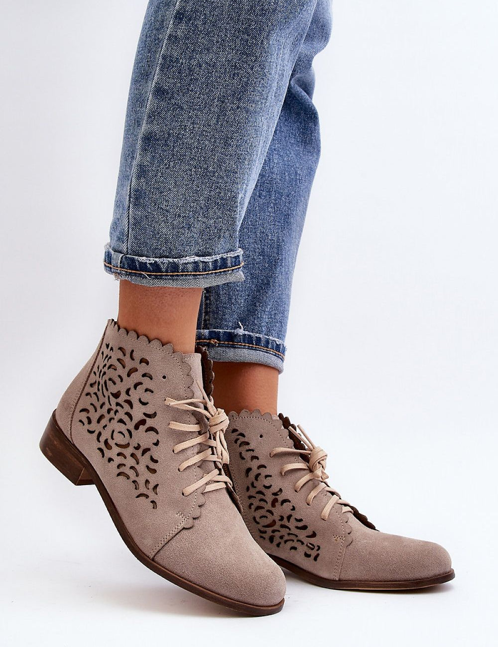 Woman wearing Caressa Suede Lace-Up Flat Boots with cutout design, paired with jeans, showcasing stylish ankle boot silhouette.