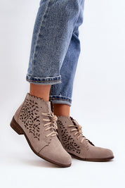 Woman wearing Caressa Suede Lace-Up Flat Boots with cutout design, paired with jeans, showcasing stylish ankle boot silhouette.