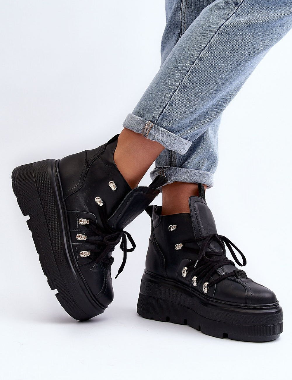 Person wearing Ermelle Sculpted Platform Sneakers in black leather with bold platform and high upper.