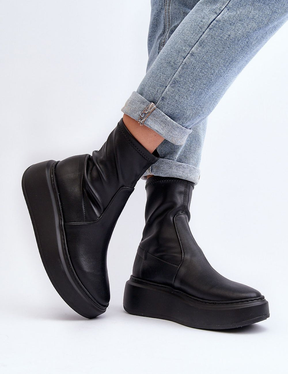 Black Zovela Leather Platform Slip-On Boots with 6 cm heel, worn with rolled jeans, showcasing modern style and comfort.