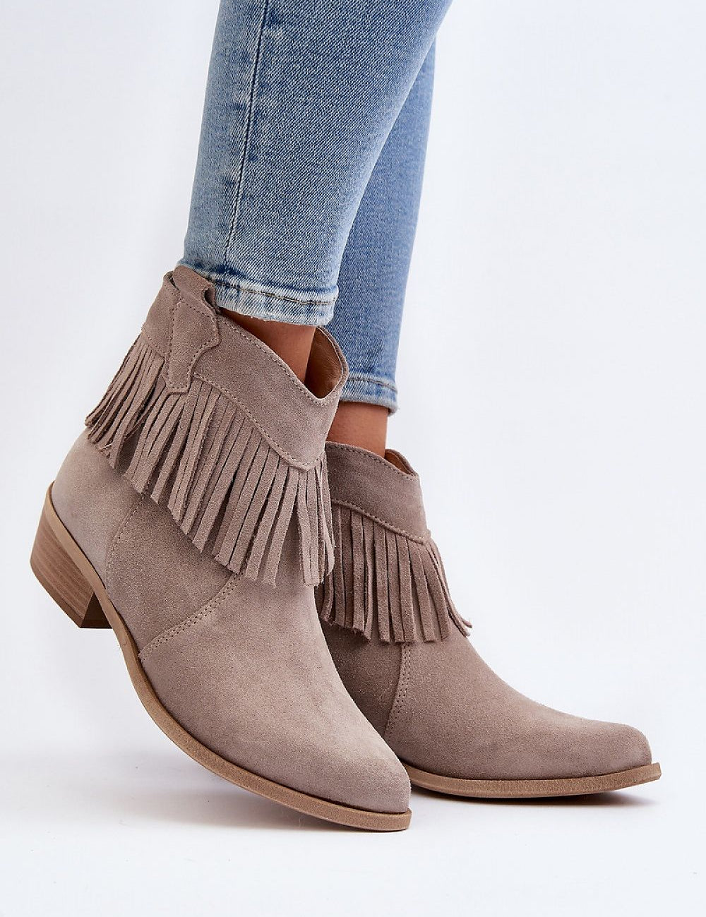 Tassava suede boots with tassel accent, pointed toe, and side zipper, worn with blue jeans, showcasing elegant design and versatility.