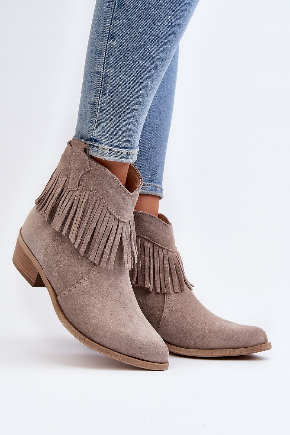Tassava suede boots with tassel accent, pointed toe, and side zipper, worn with blue jeans, showcasing elegant design and versatility.