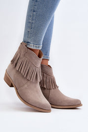 Tassava suede boots with tassel accent, pointed toe, and side zipper, worn with blue jeans, showcasing elegant design and versatility.
