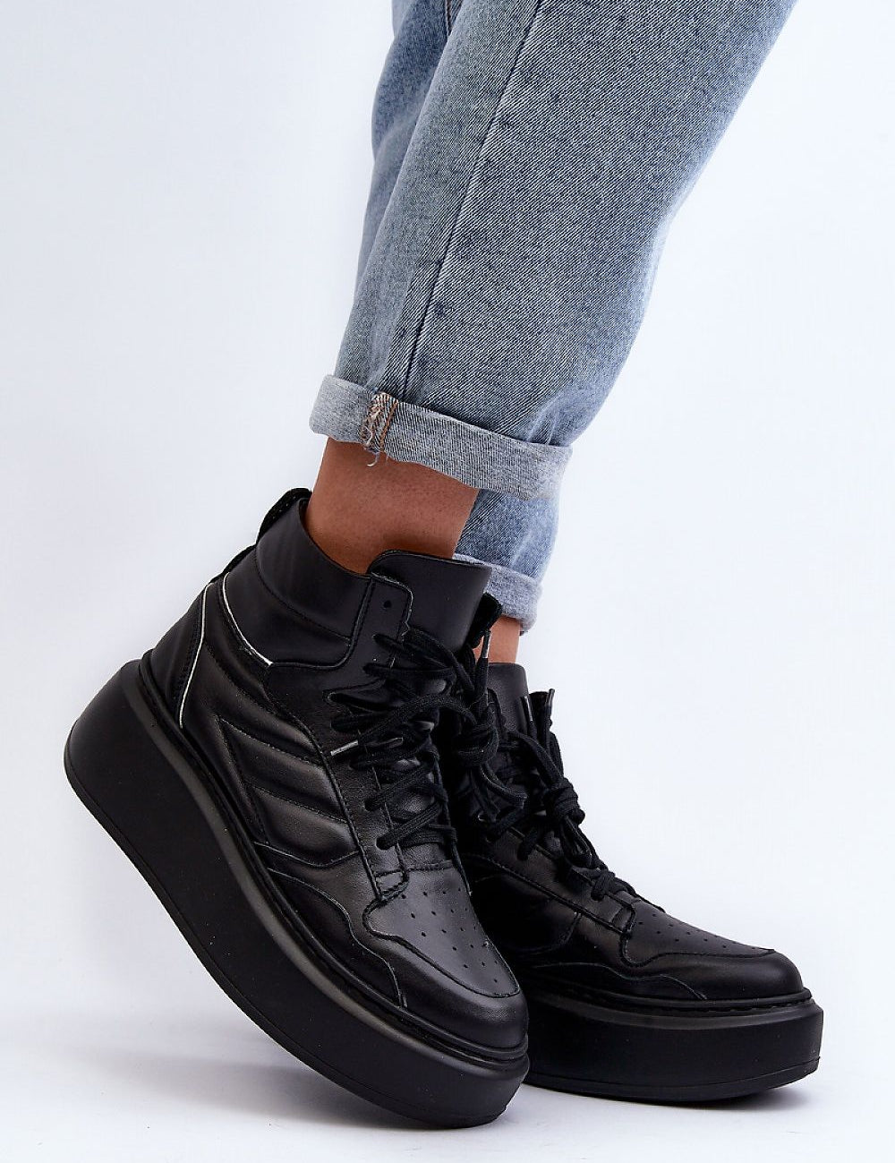 Black Valonne Leather Platform Trainers with 7cm heel and thick base, ankle-high, paired with rolled-up jeans for a stylish look.