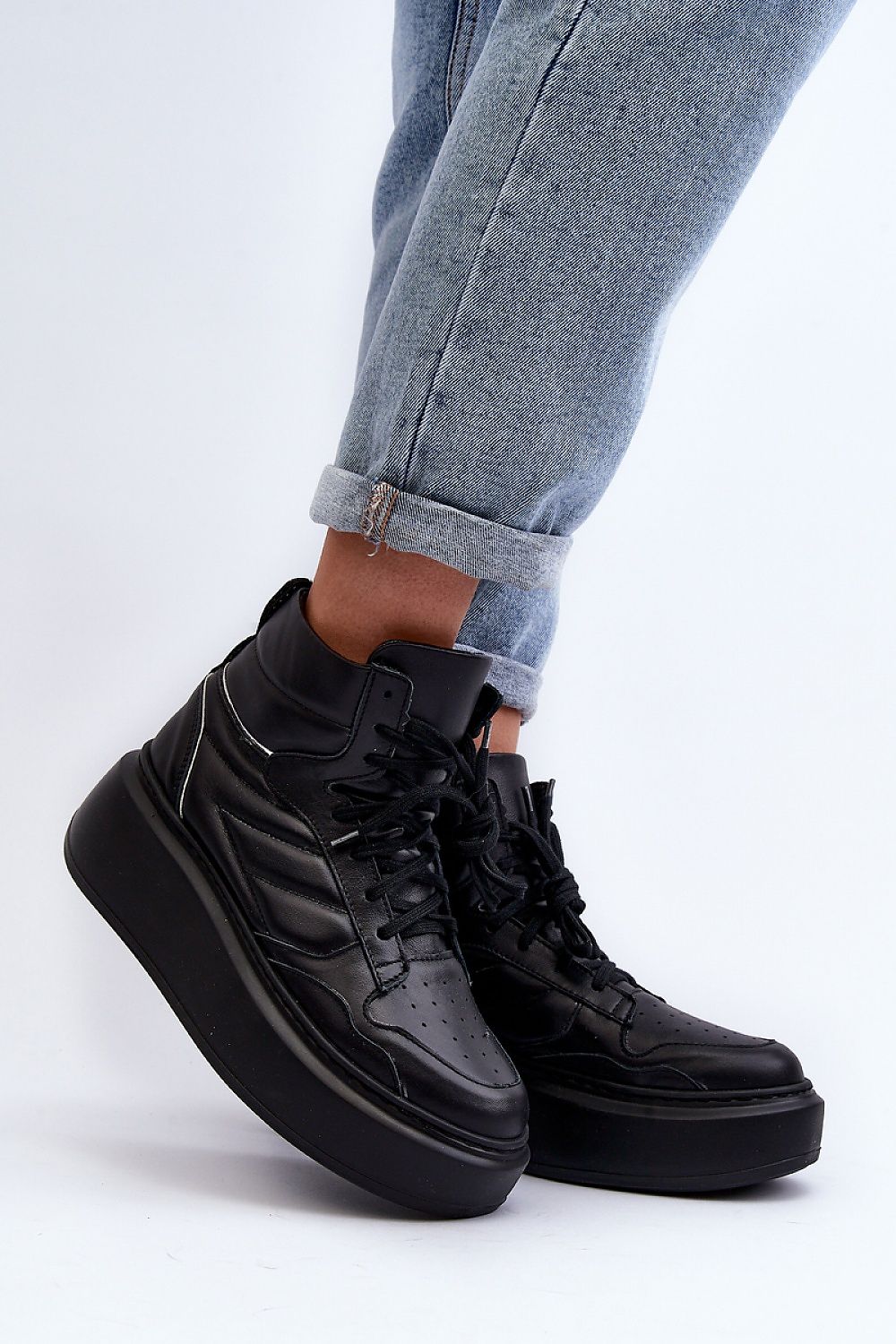 Black Valonne Leather Platform Trainers with 7cm heel and thick base, ankle-high, paired with rolled-up jeans for a stylish look.
