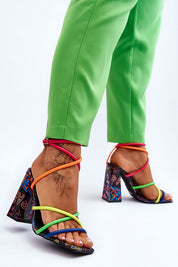 Colorful high heel sandals with strappy design and bold heel, worn with green pants for a vibrant fashion statement.