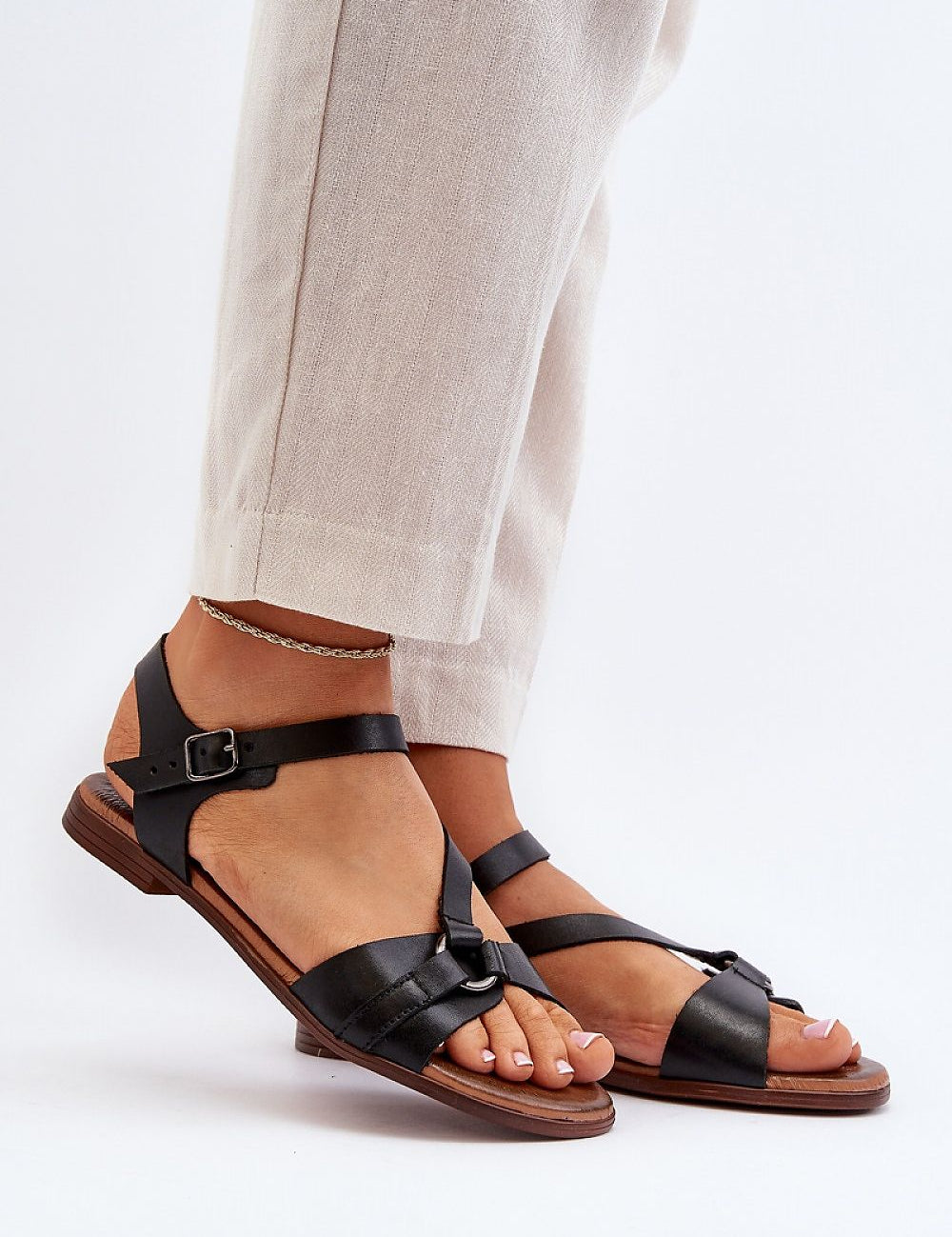 Person wearing Sylvara Classic Leather Flat Sandals with adjustable buckle strap and low-profile heel for summer comfort.
