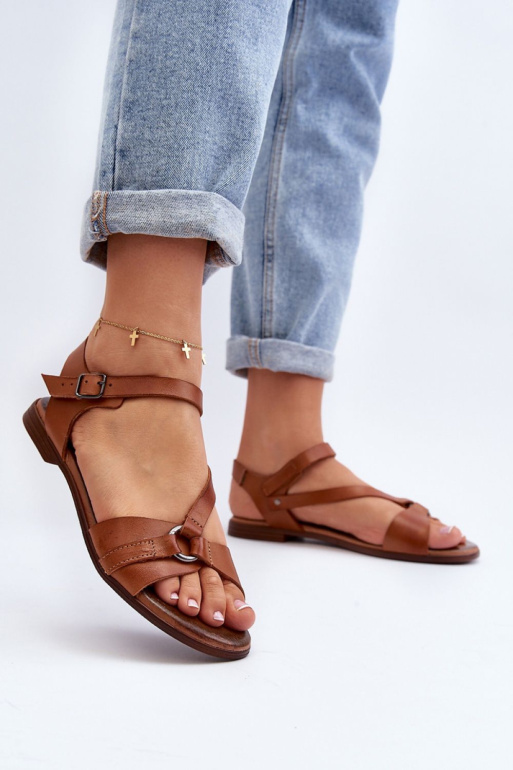 Model wearing Sylvara Classic Leather Flat Sandals with adjustable buckle strap and low-profile heel, styled with cuffed jeans.