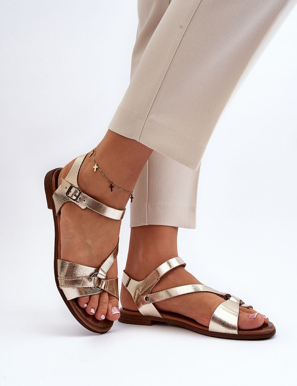Woman wearing Sylvara Classic Leather Flat Sandals with adjustable buckle strap in gold, perfect for casual summer elegance.