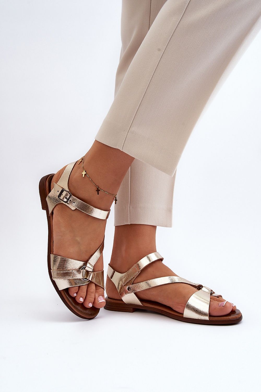 Woman wearing Sylvara Classic Leather Flat Sandals with adjustable buckle strap in gold, perfect for casual summer elegance.