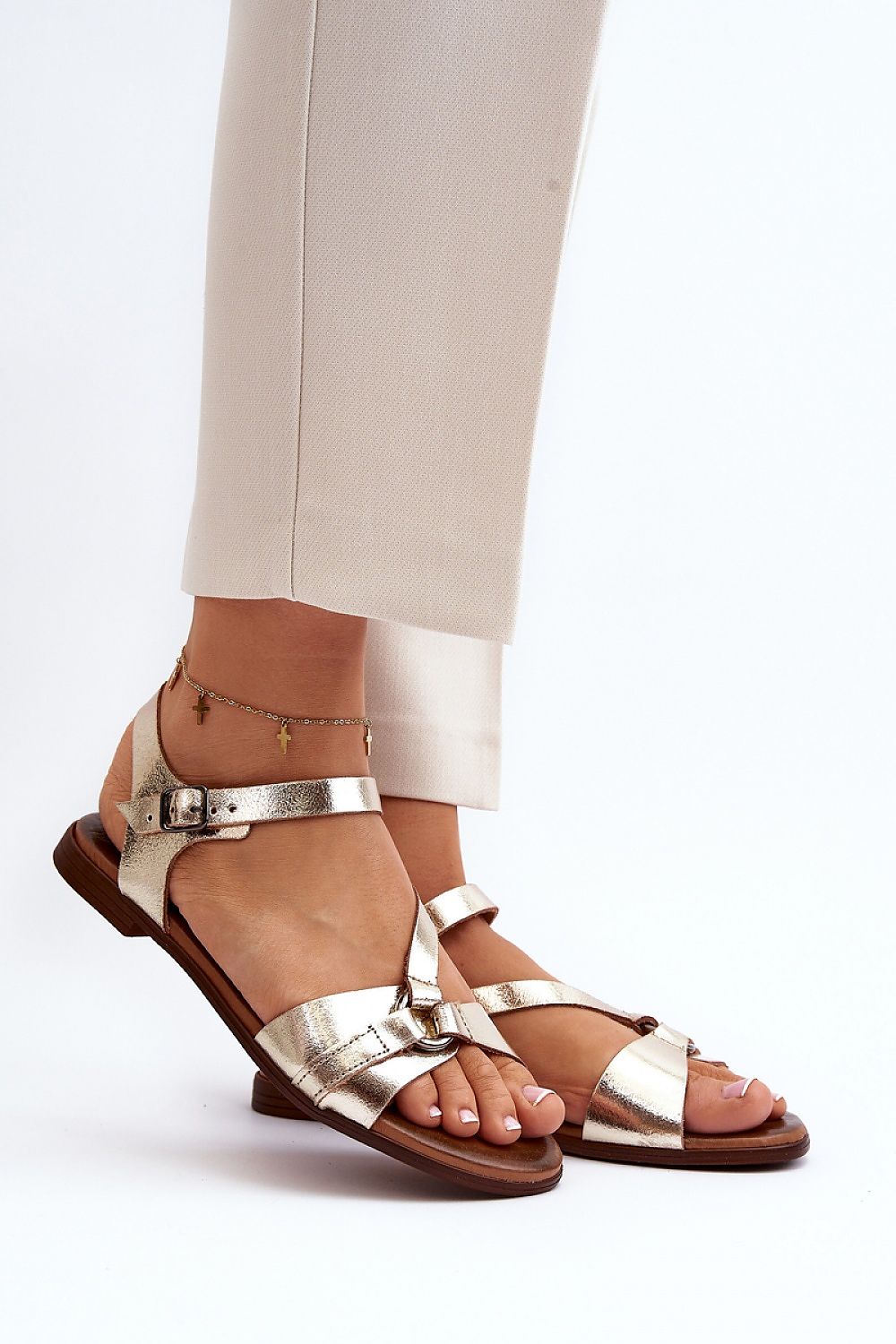Woman wearing Sylvara Classic Leather Flat Sandals in gold with adjustable buckle and low-profile heel, styled for summer.