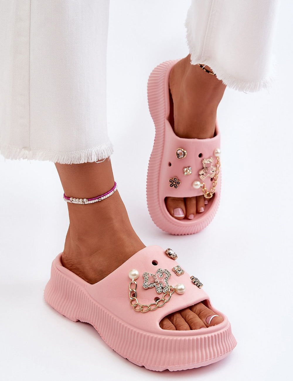 Orminya pink foam platform slides with decorative accents, offering comfort and height, worn with white pants.