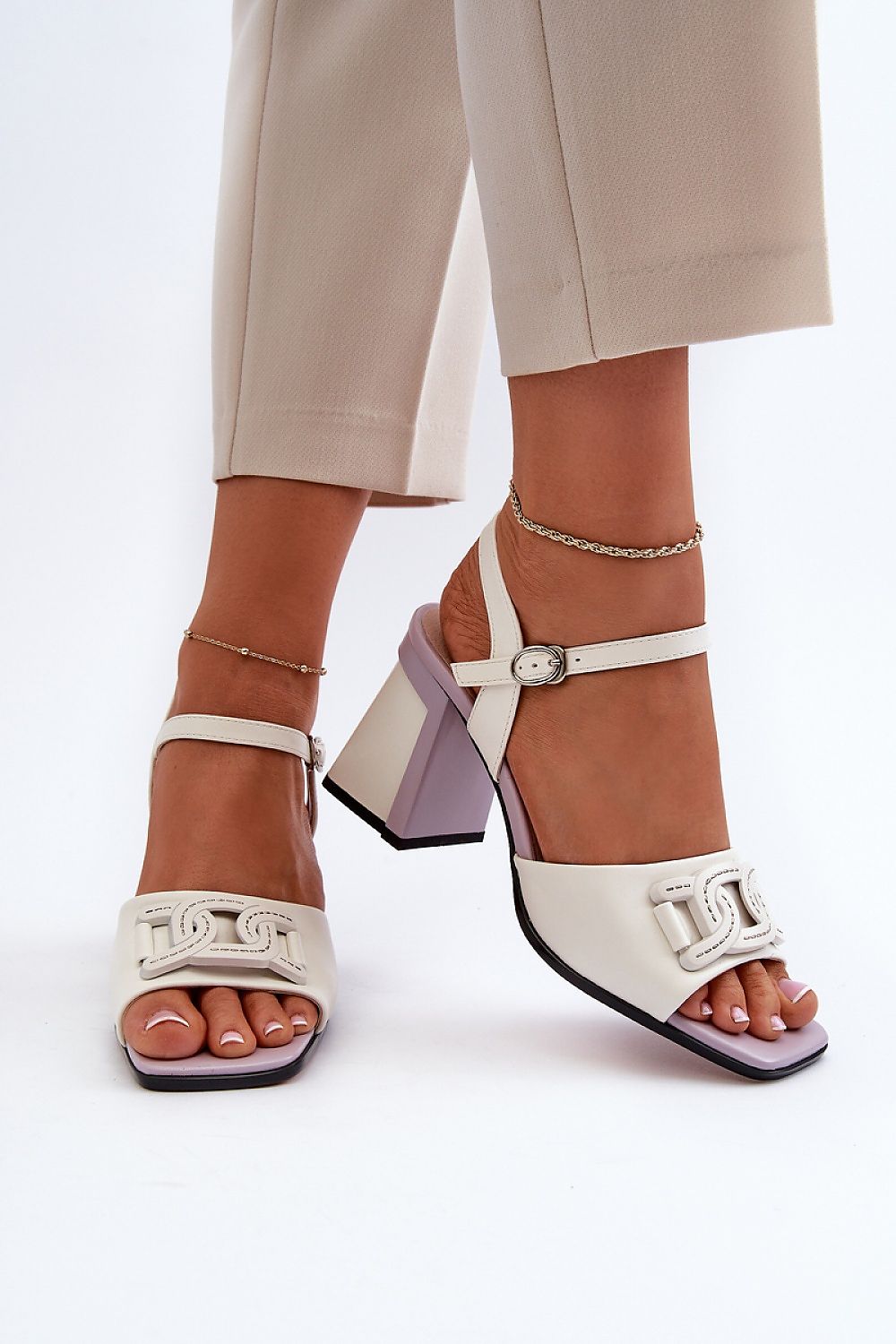 Woman wearing Aurelenna Post Heel Sandals with accent, featuring eco leather, high post heel, ankle strap, and decorative front element.