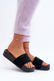 Person wearing Zanurea Suede Platform Slide Sandals with black suede strap and solid platform base, showcasing casual style.