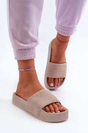 Woman wearing Zanurea suede platform slide sandals with purple joggers.