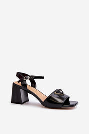 Cirellia Gloss Block Heel Sandals in black lacquered eco leather with decorative front accent, mid-height heel, and adjustable strap.