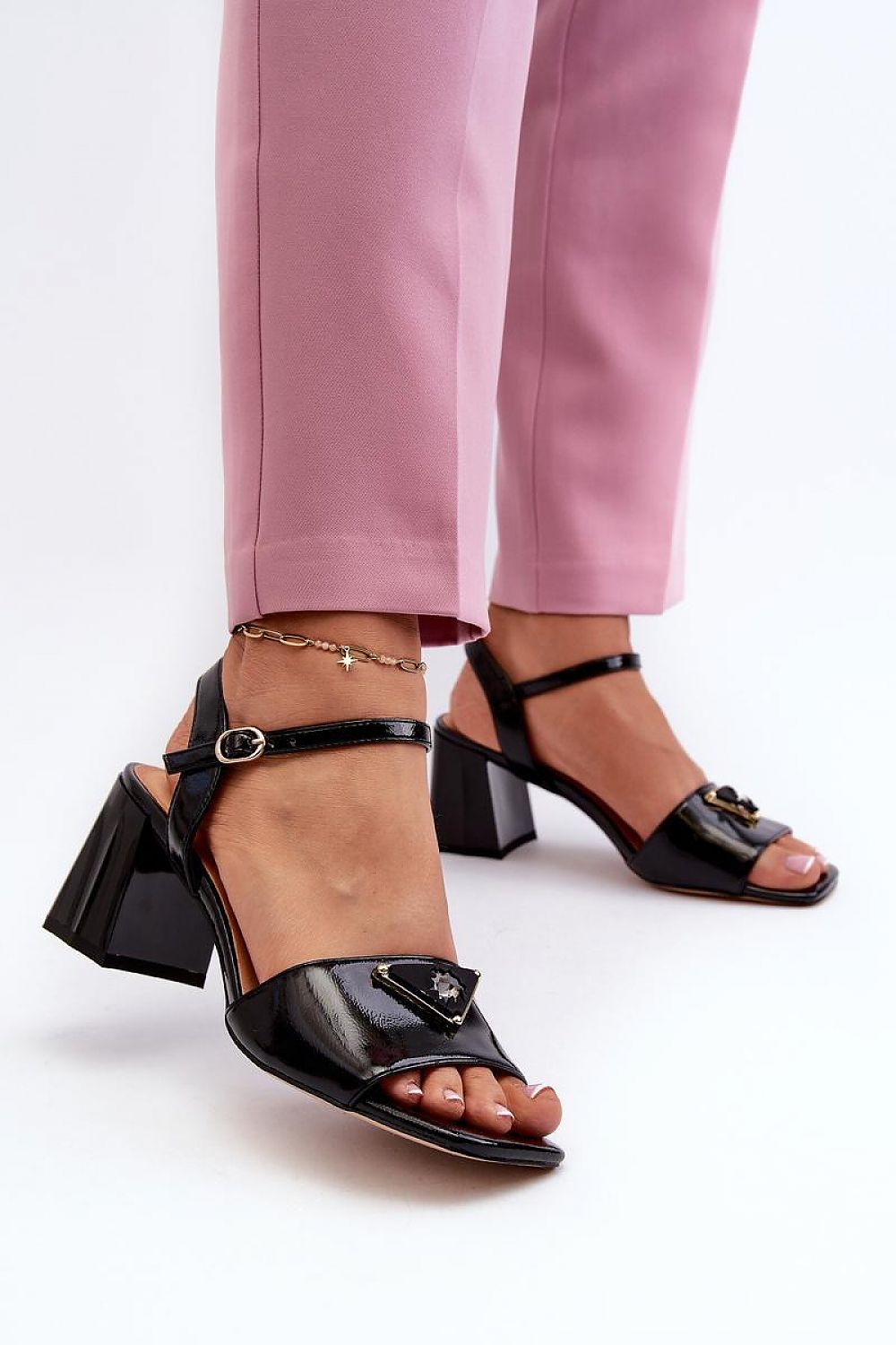 Cirellia Gloss Block Heel Sandals in black lacquered eco leather with decorative accent, adjustable strap, and mid-height block heel.
