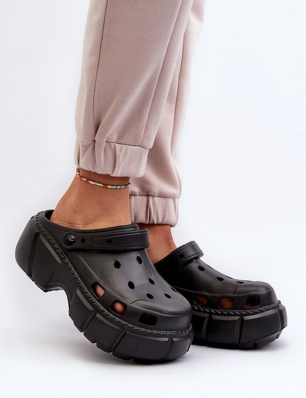 Black sculpted foam beach slides worn with light pants, featuring a thick sole for support and minimalist design ideal for summer.