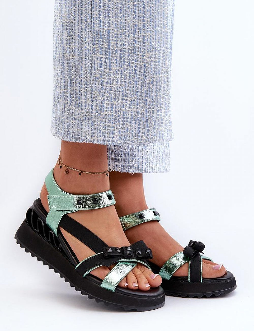 Woman wearing Aurelline Strap Bow Wedge Sandals in green, featuring a delicate bow and Velcro strap with a stylish wedge heel.