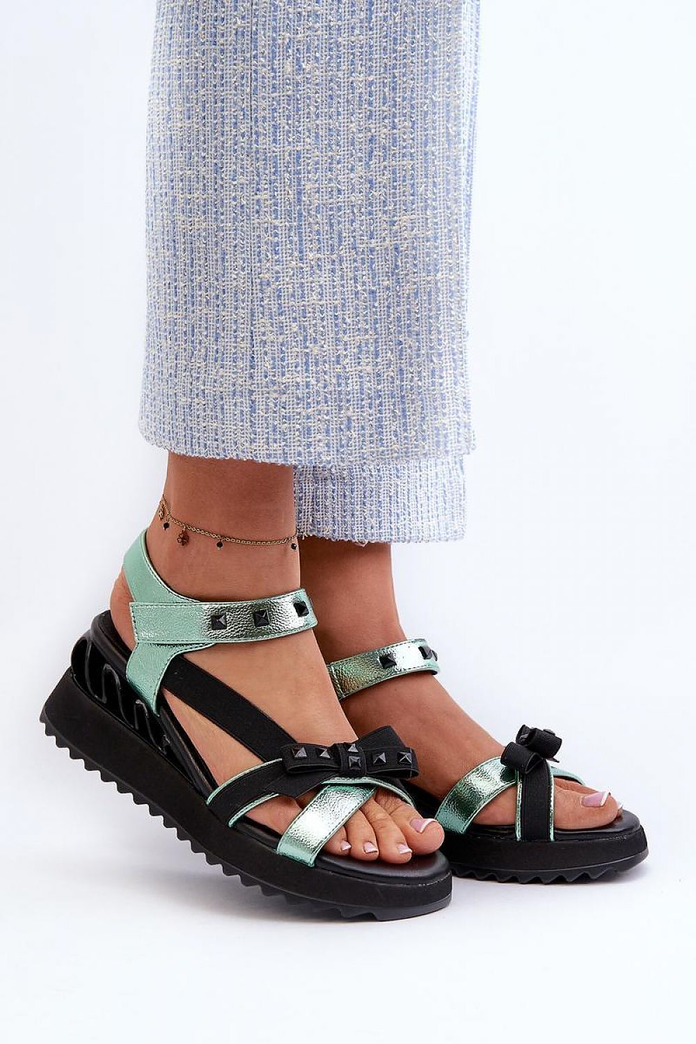 Woman wearing Aurelline Strap Bow Wedge Sandals in green, featuring a delicate bow and Velcro strap with a stylish wedge heel.