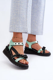 Woman wearing Aurelline Strap Bow Wedge Sandals with artificial leather, delicate bow detail, and Velcro strap for easy closure.