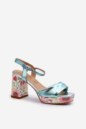 Florvella patterned block heel sandal in metallic blue with floral design, featuring buckle strap and artificial leather upper.