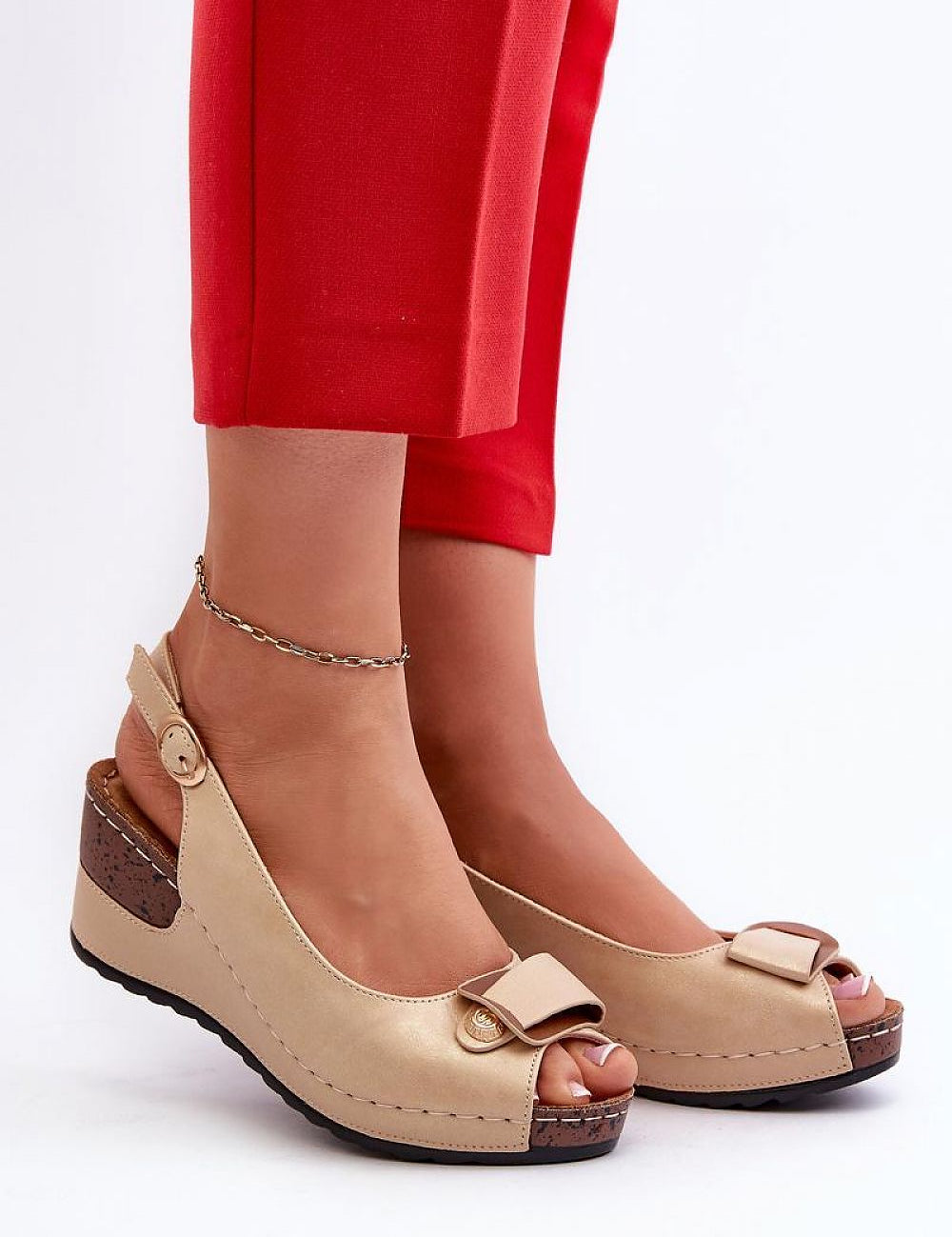Tan wedge sandals with adjustable eco leather straps and cushioned insole, worn with red pants. Perfect blend of height and comfort.