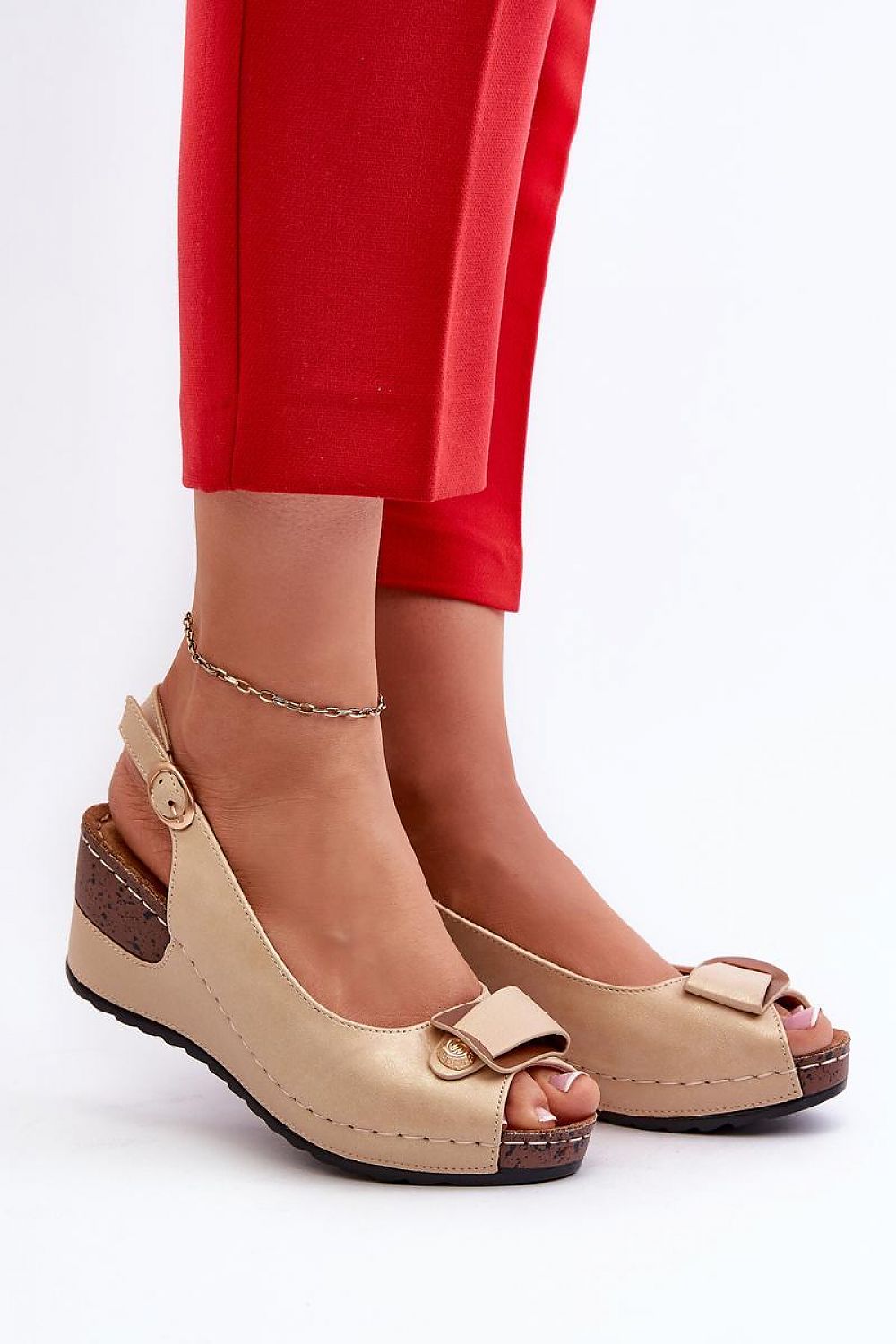 Tan wedge sandals with adjustable eco leather straps and cushioned insole, worn with red pants. Perfect blend of height and comfort.
