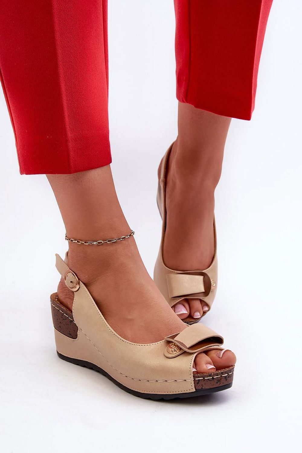 Woman wearing Vesmira Lifted Comfort Wedges with eco leather straps, cushioned insole, and adjustable buckle, paired with red pants.