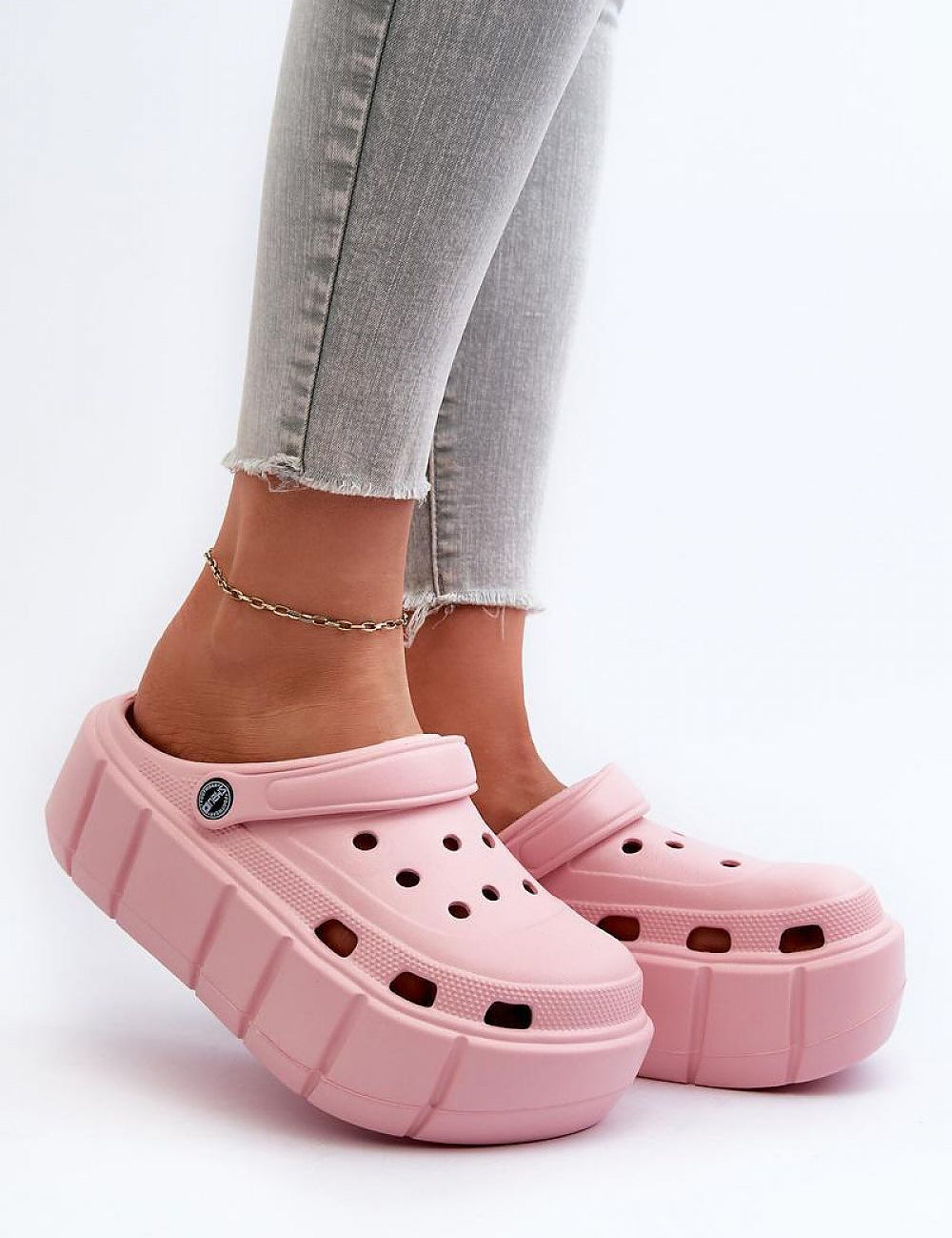 Pink platform sculpted foam slides worn with jeans, offering cushioned comfort and bold design for a fashionable look.
