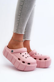 Pink platform sculpted foam slides worn with jeans, offering cushioned comfort and bold design for a fashionable look.