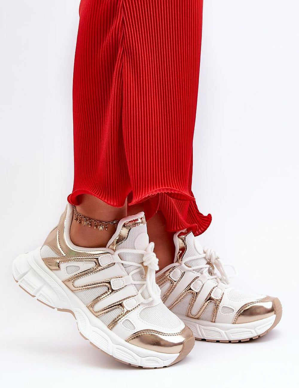 Person wearing Astaria thick-soled street sneakers with white and metallic accents paired with red pants for an urban look.