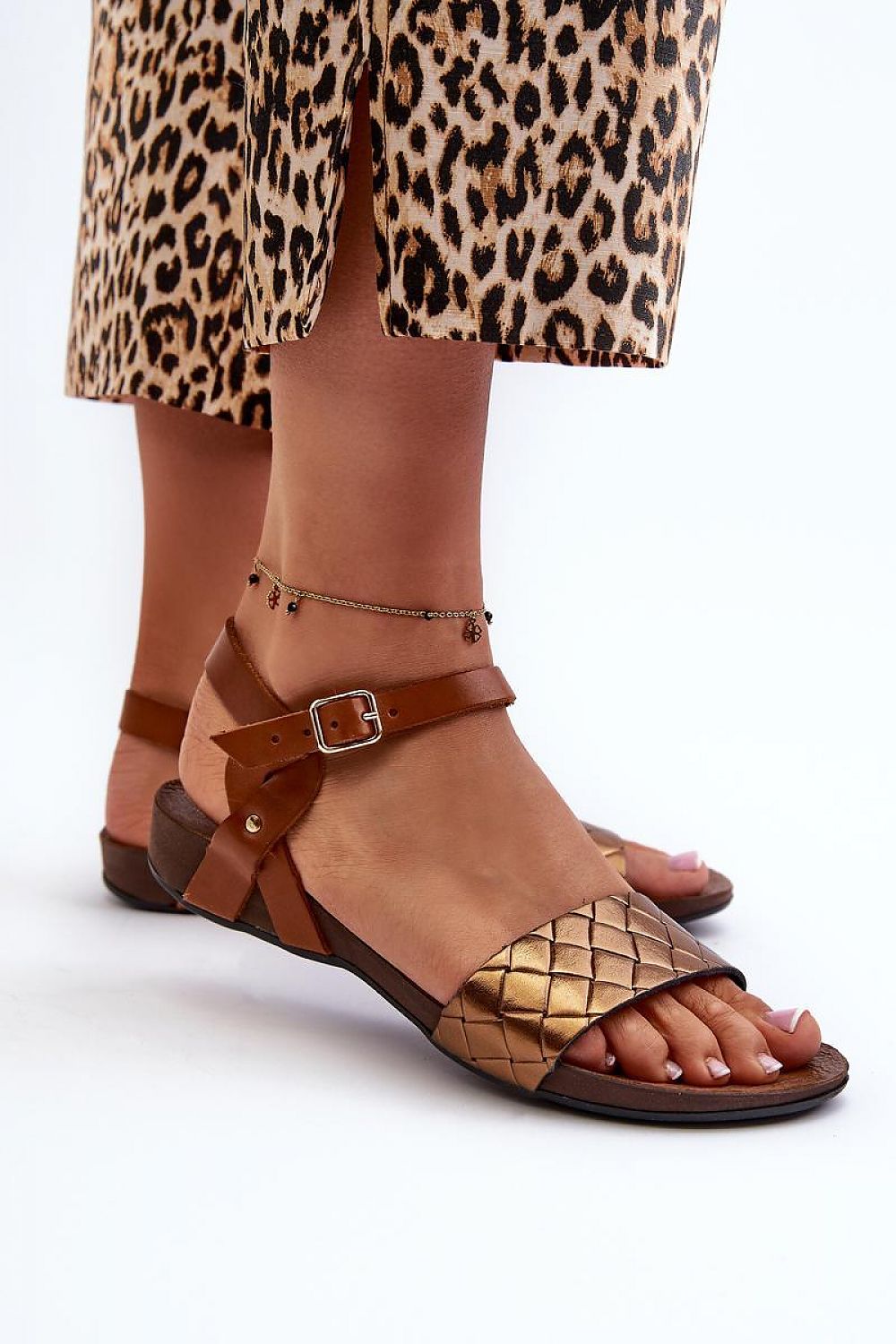 Woman wearing Sorellia Buckled Leather Sandals with adjustable buckle strap, paired with a leopard print skirt, for summer city walks.