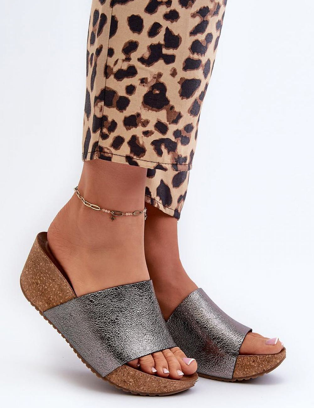Woman wearing Mirano leather wedge flip-flops with cork-style wedge and silver straps, paired with leopard print pants.