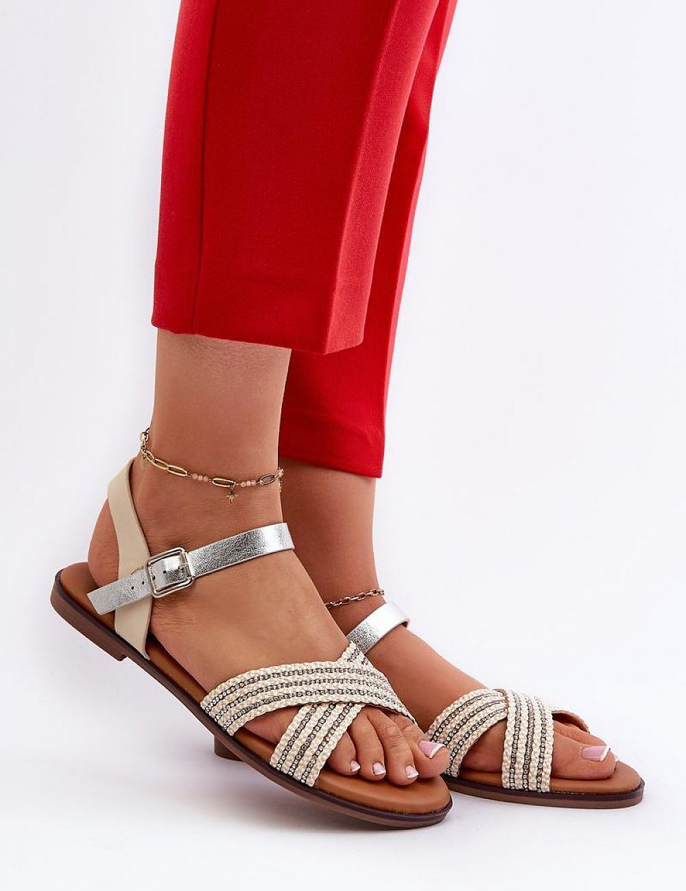 Woman wearing Serelvia Minimal Strap Sandals in eco leather, showcasing sleek, adjustable buckle design and flat sole, paired with red pants.