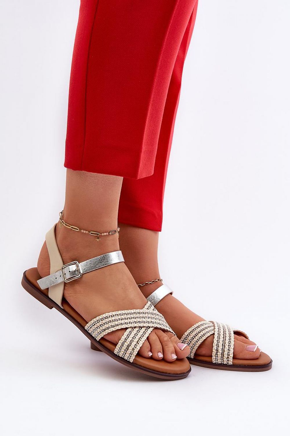 Woman wearing Serelvia Minimal Strap Sandals in eco leather, showcasing sleek, adjustable buckle design and flat sole, paired with red pants.