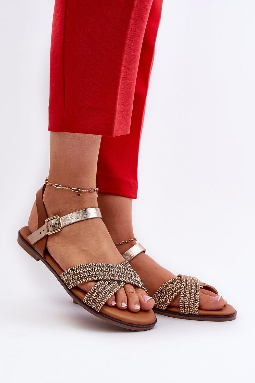 Woman modeling Serelvia Minimal Strap Sandals with eco leather, adjustable buckle, and flat sole paired with red pants.