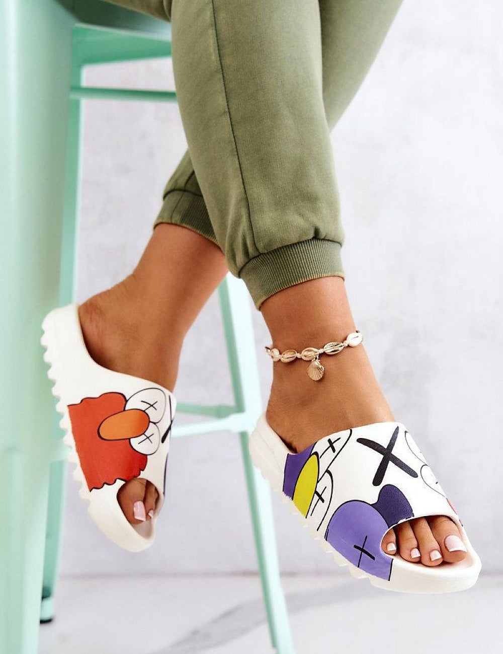 Cartoon-inspired rubber summer slides with playful print on a woman's foot, showcasing a fun and colorful design, worn indoors.