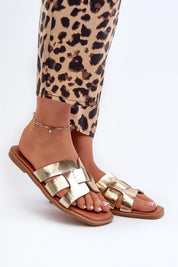 Gold metallic sandals with crisscross straps worn with leopard print pants, showcasing stylish and trendy footwear.