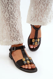 Black summer sandals with gemstone embellishments and adjustable straps, worn with white lace pants, ideal for casual summer outings.