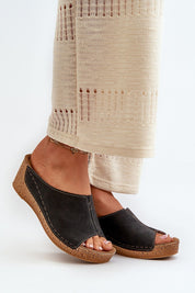 Woman wearing black wedge sandals with beige wide-leg pants on white background