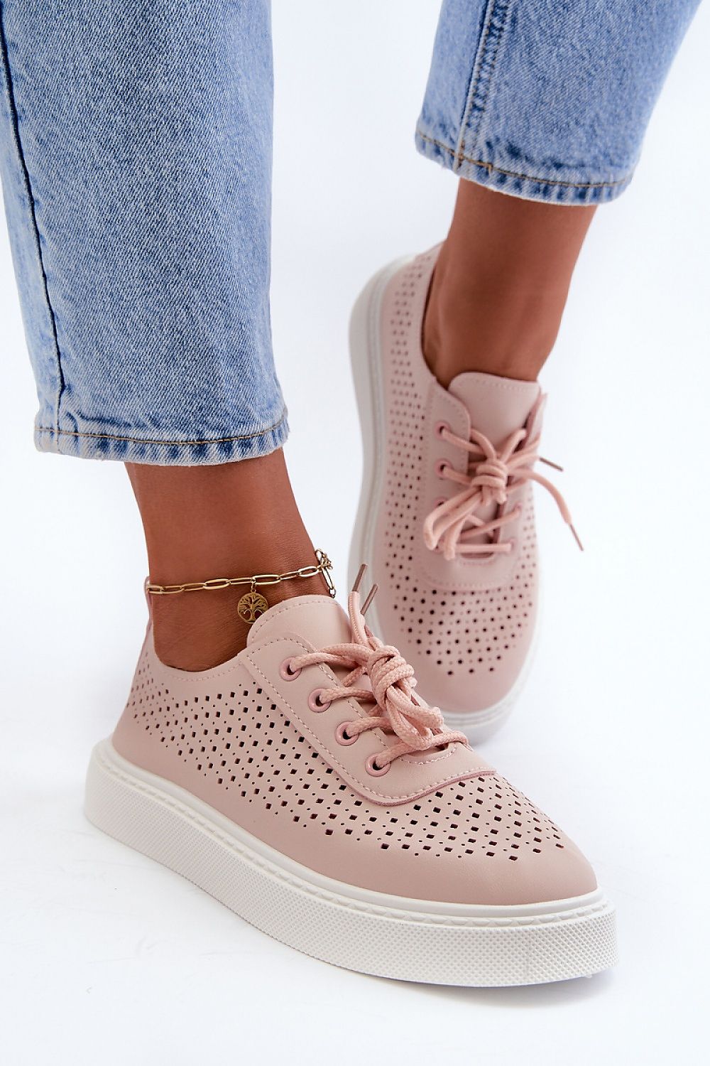 Woman wearing Ferossa openwork platform sneakers made of pink artificial leather with perforated design, paired with blue jeans.