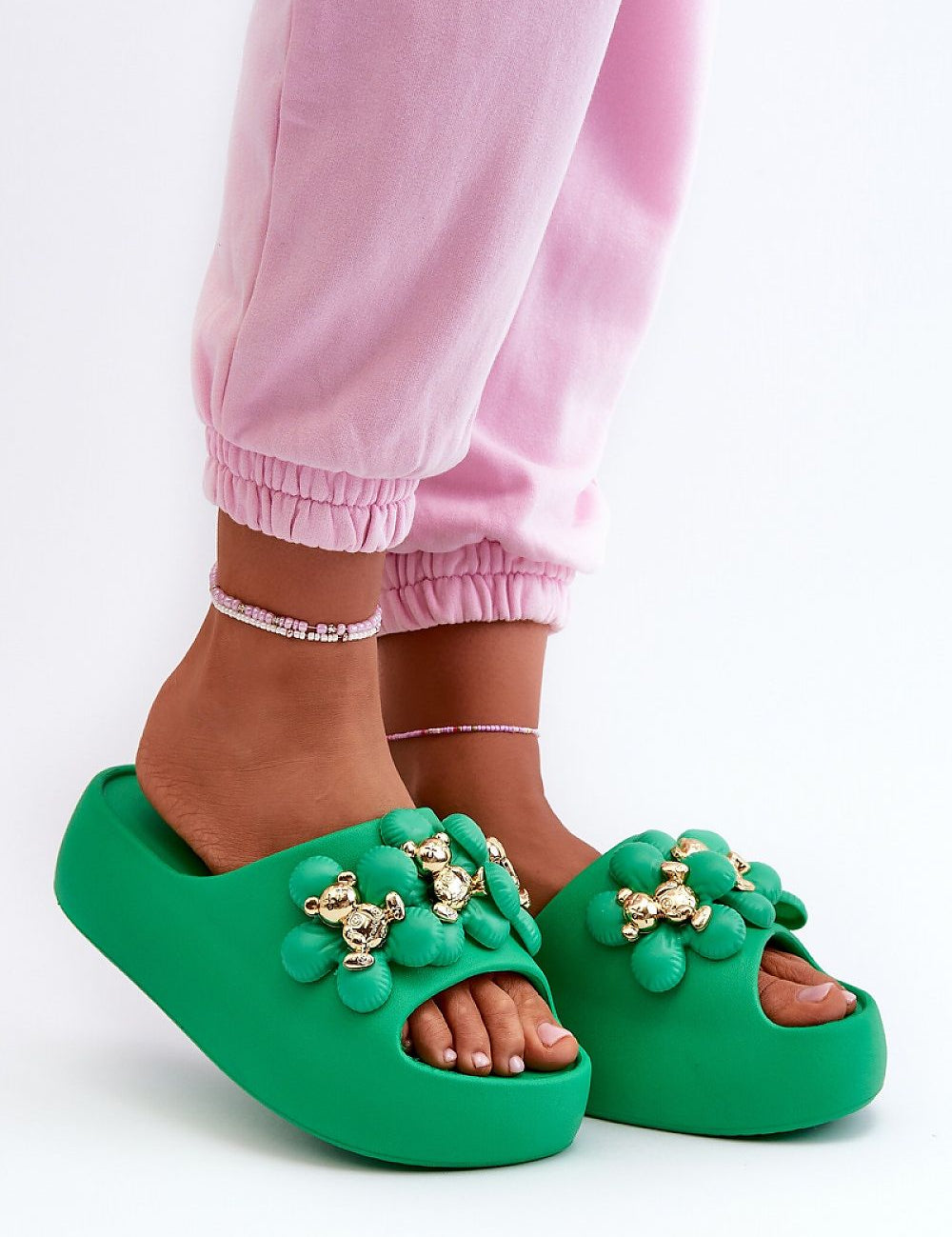 Person wearing green platform flip-flops with decorative accents, showcasing stylish and comfortable summer footwear.