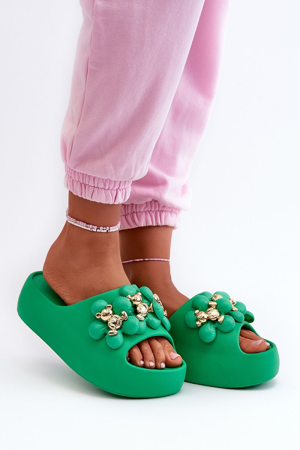 Person wearing green platform flip-flops with decorative accents, showcasing stylish and comfortable summer footwear.