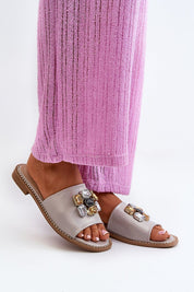 Elegant Velinor Decor Flat Sandals with glossy synthetic upper and decorative accents, worn with pink textured pants.