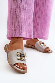 Velinor Decor Flat Sandals with glossy synthetic upper, decorative accents, and leather insole for summer; worn with pink pants.